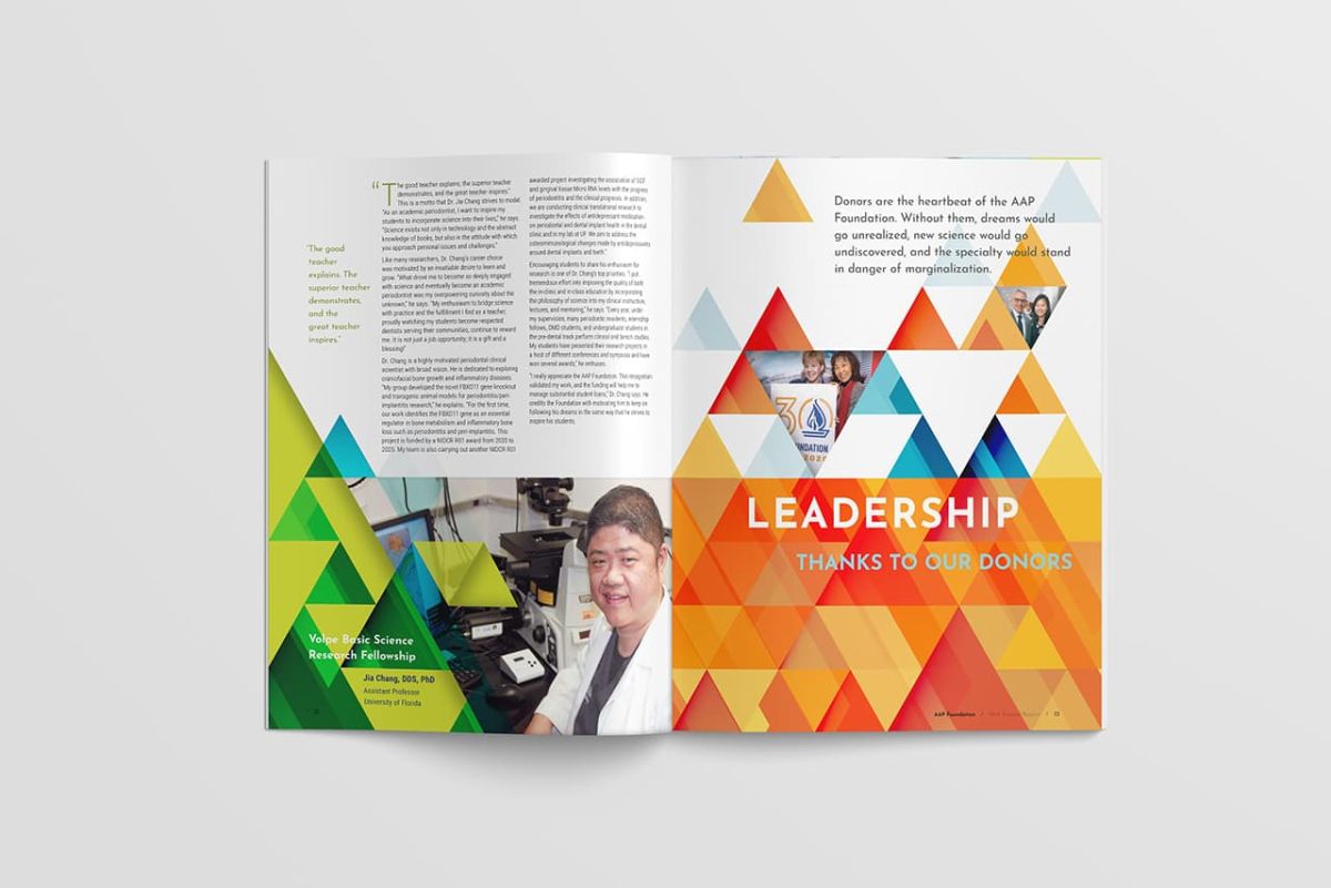 an open annual report with colorful designs of various shades of orange and green